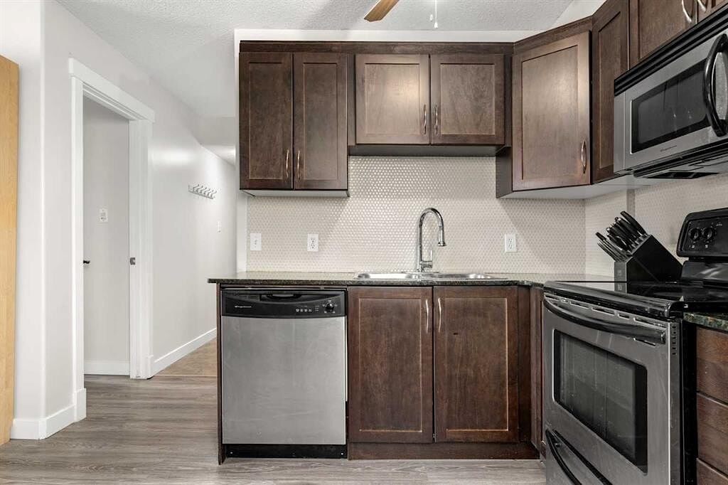 A kitchen with dark wood cabinets and stainless steel appliances.