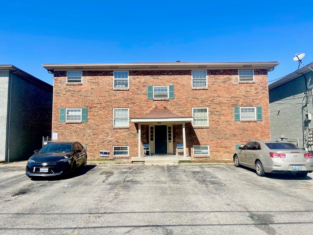 an old brick building with two cars parked in front of it