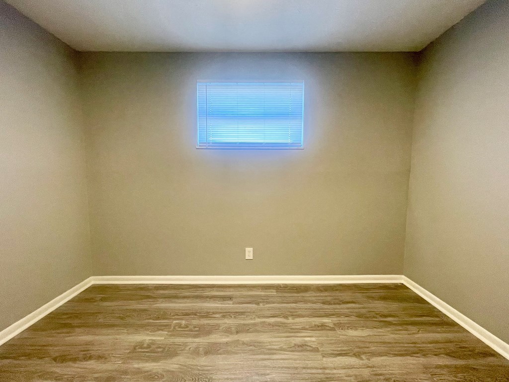 a empty room with a window and wooden floors