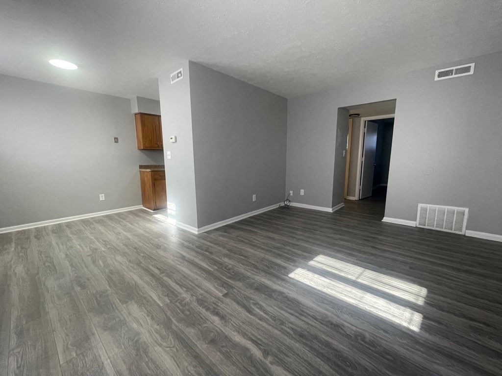 an empty living room with wood flooring and grey walls