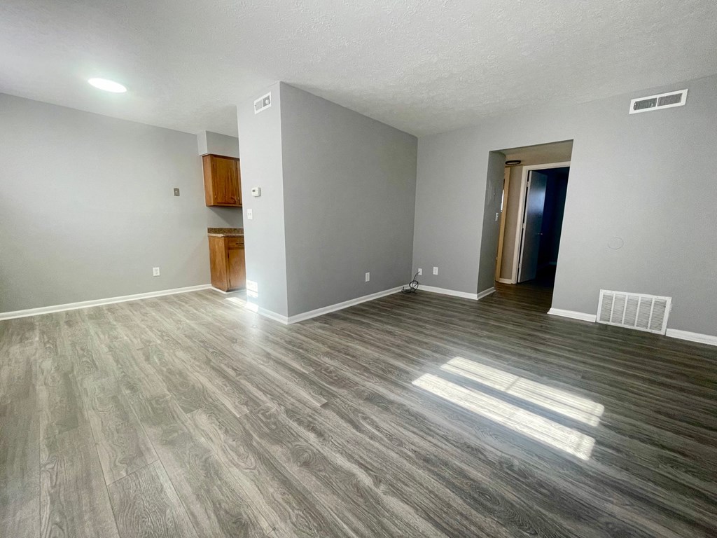 an empty living room with wood flooring and grey walls