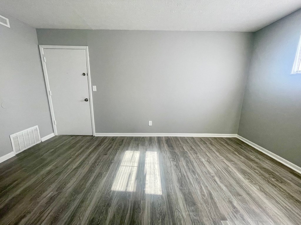 an empty room with vinyl flooring and grey walls