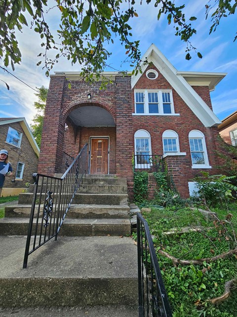 A red brick house with a black metal staircase.