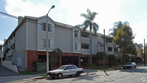 A white car is parked in front of a grey building.