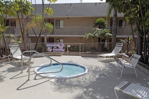 A small pool surrounded by chairs and trees.