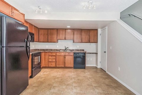 A kitchen with a black refrigerator and wooden cabinets.