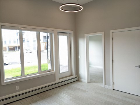 an empty living room with large windows and a door