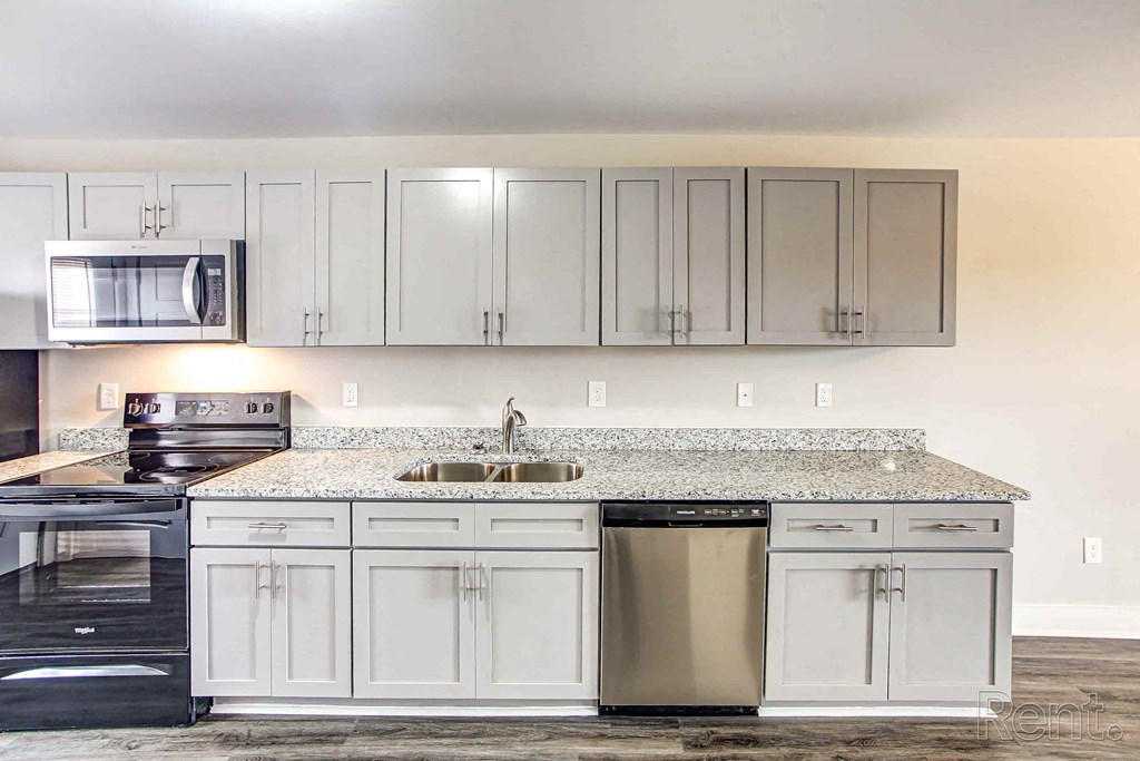 A kitchen with white cabinets and a granite countertop.