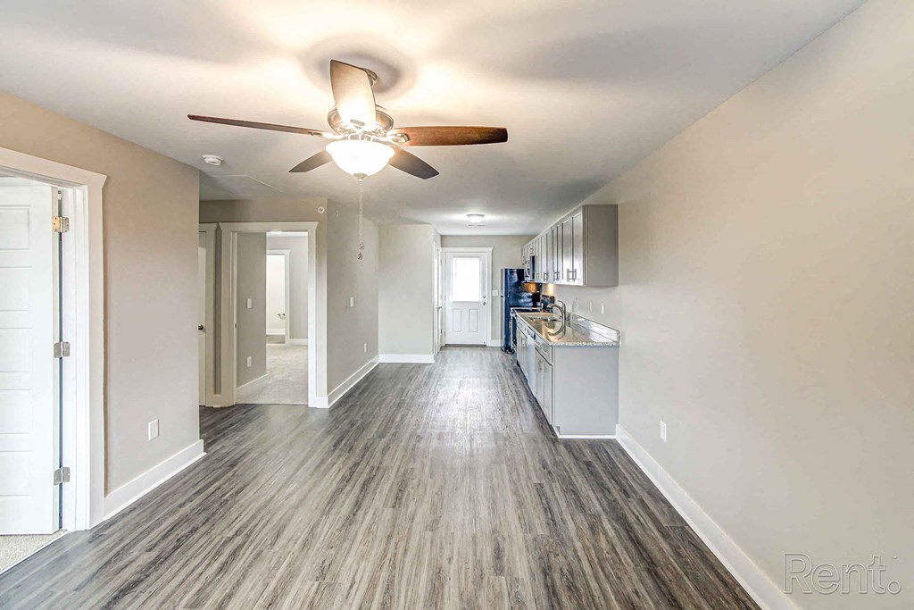 A long hallway with a fan and wood flooring.