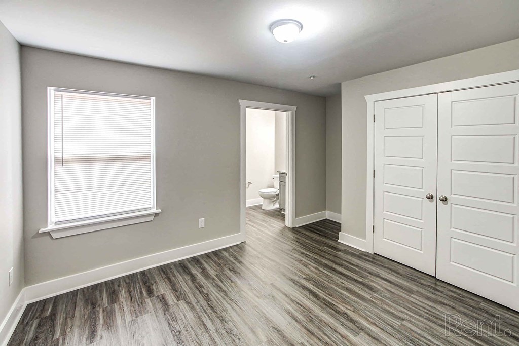 A room with a toilet and a wooden floor.