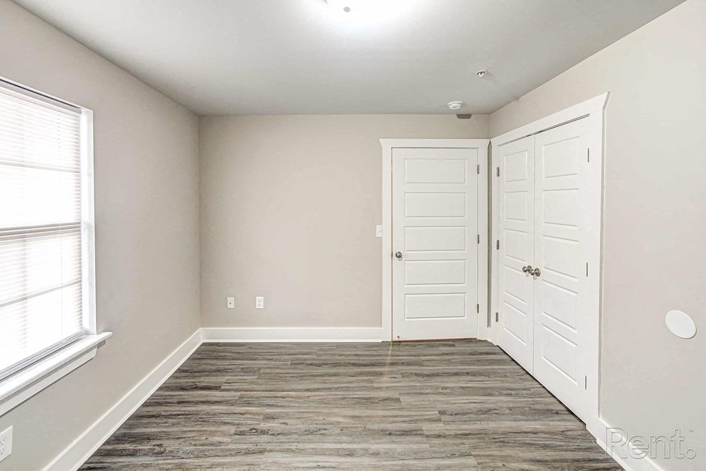 A room with two white doors and a window with blinds.