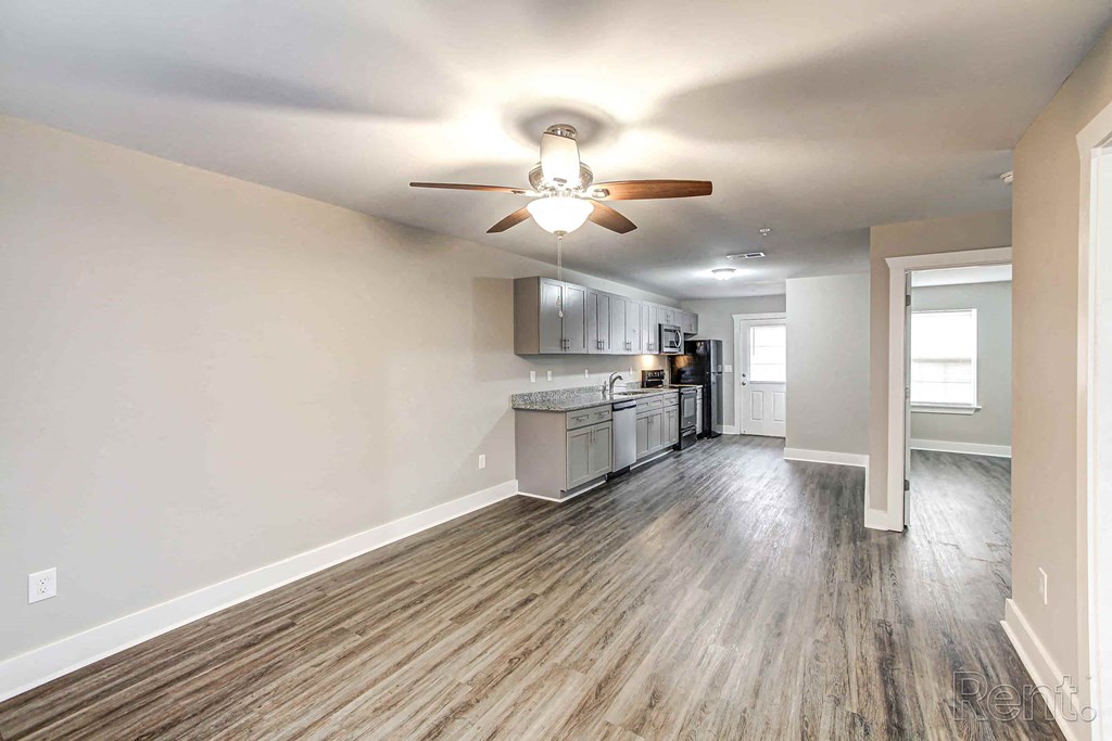 A spacious kitchen with wood flooring and a ceiling fan.