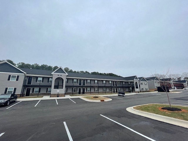 A parking lot in front of a building with a grey roof.