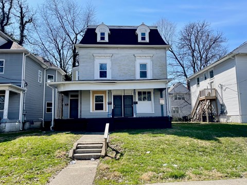 A white house with a black roof and a small porch.