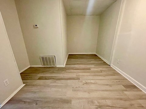 A room with a wood floor and a wall heater.