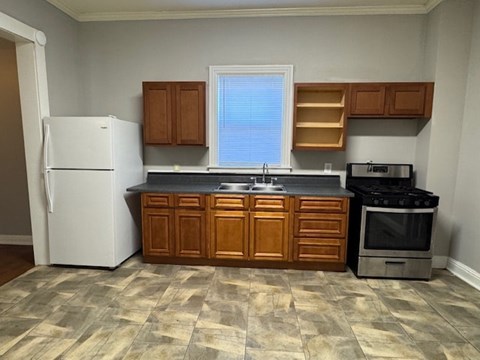 A kitchen with a white refrigerator, wooden cabinets, and a black stove top oven.