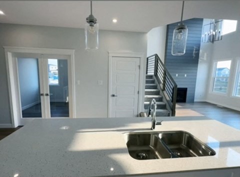 A kitchen with a sink and a staircase.