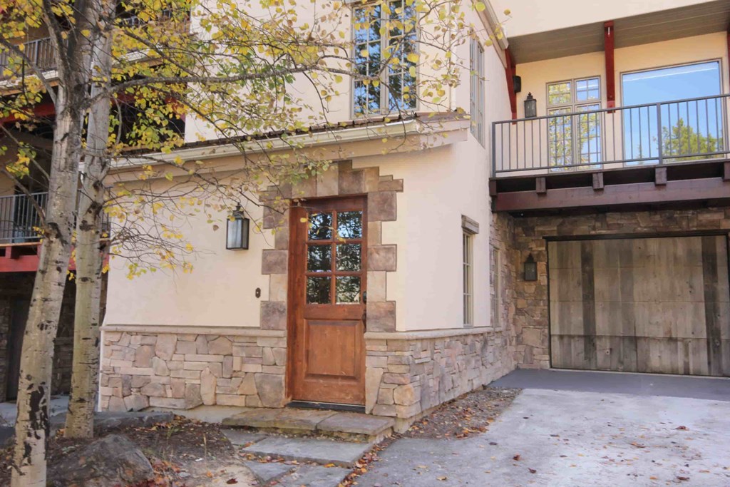 the front door of a house with a driveway and a tree