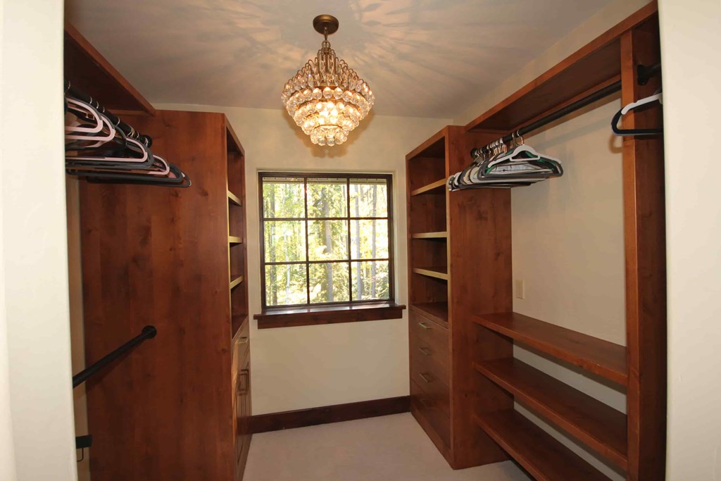 a walk in closet with a chandelier and a window