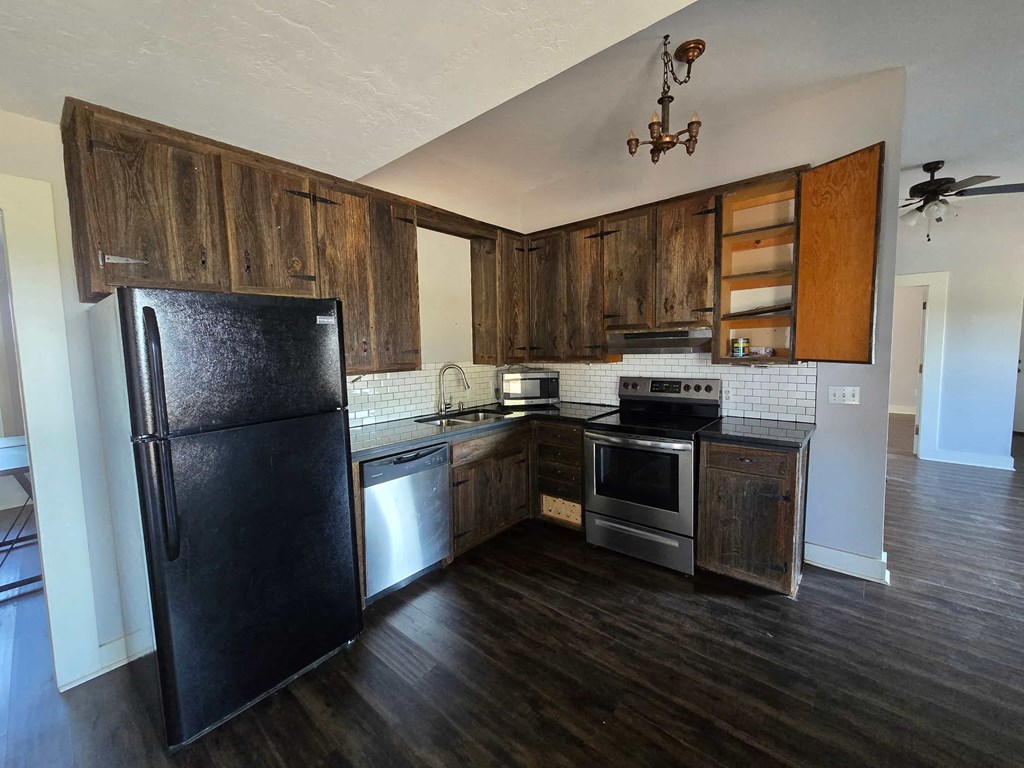 a kitchen with wooden cabinets and a black refrigerator