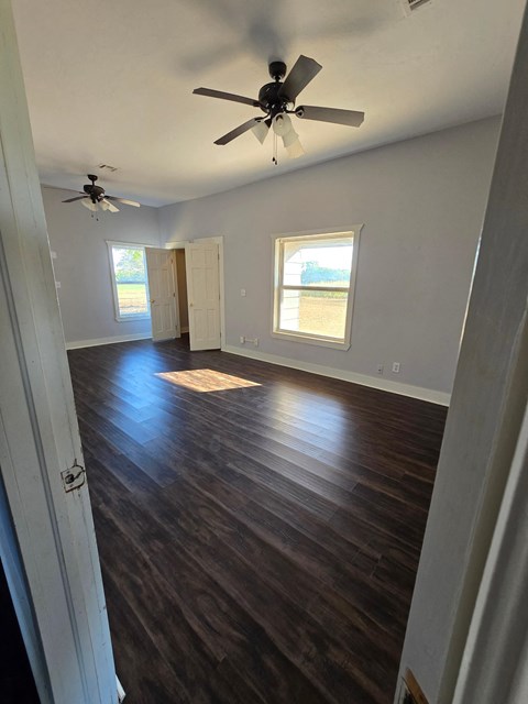 an empty living room with wooden floors and a ceiling fan
