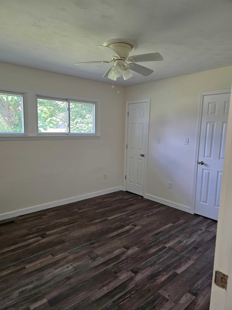 A room with a ceiling fan and wood flooring.