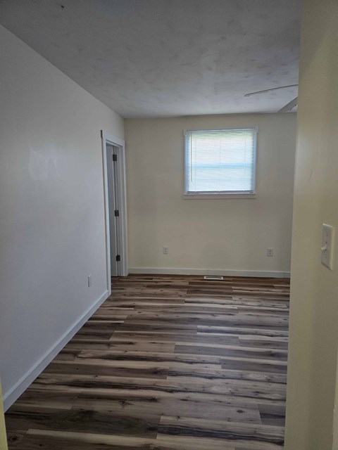 A room with wooden flooring and a window.