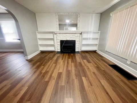 A room with wooden flooring and a fireplace.
