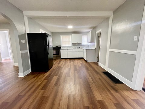 A kitchen with a black fridge and wooden floors.