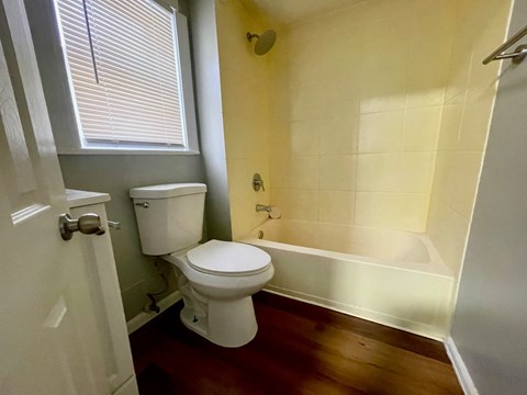 A white toilet sits in a bathroom with yellow walls and a white door.