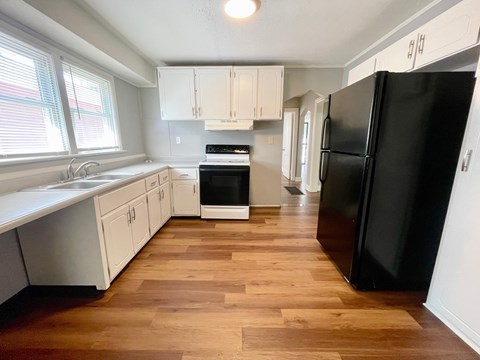 A kitchen with a black refrigerator and wooden floors.