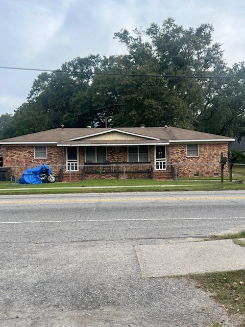 A brick house with a blue tarp on the lawn.