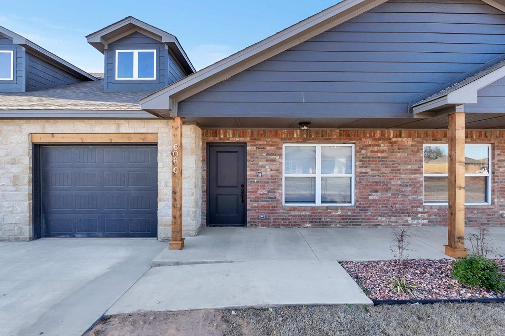 the front of a brick house with two garage doors