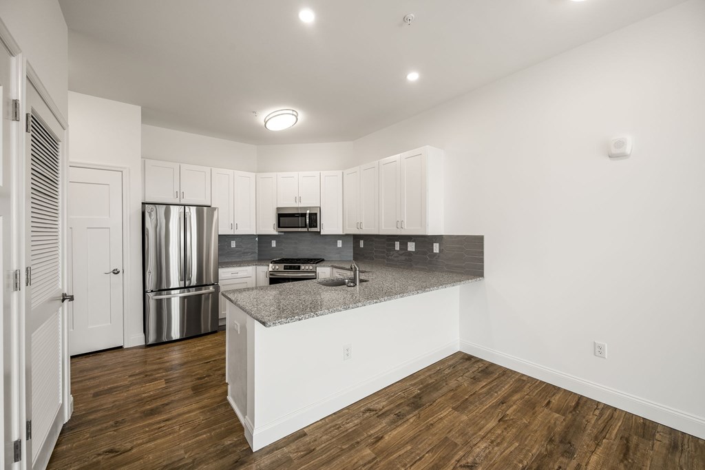 A kitchen with white cabinets and a wooden floor.