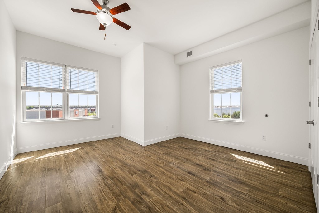 A room with a ceiling fan and wooden flooring.
