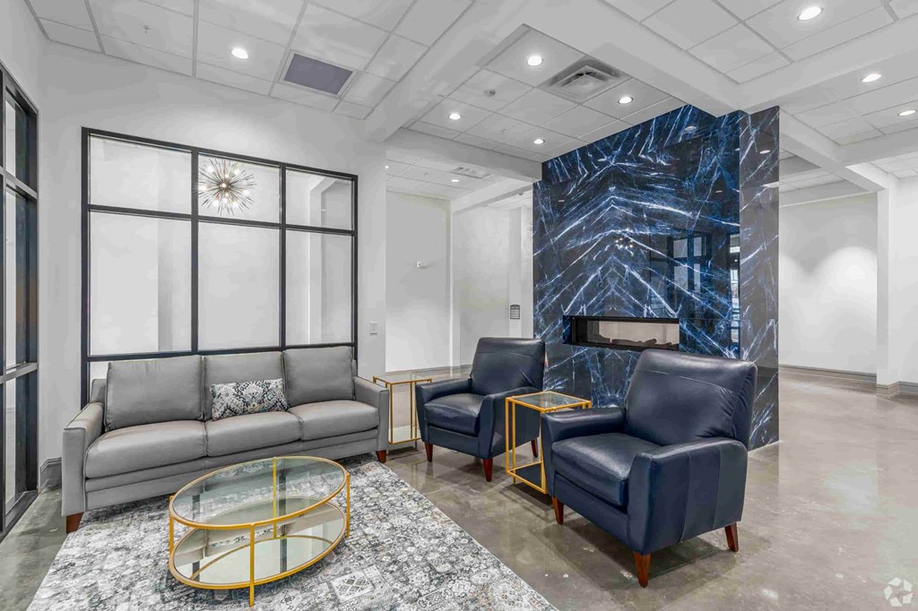 A living room with a grey couch, a blue chair and a glass coffee table.