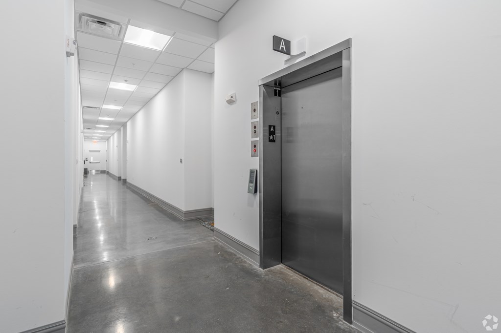 A long hallway with a metal door on the right.