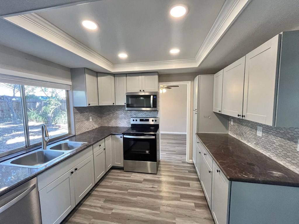 a kitchen with white cabinets and black counter tops