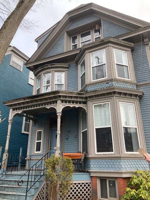 A blue house with a porch and a balcony.