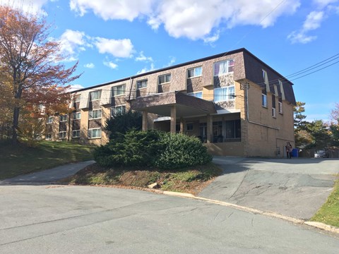 A large apartment building with a parking lot in front.