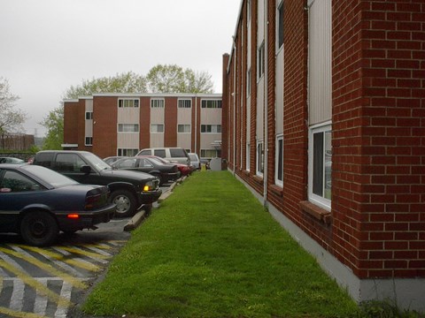 A parking lot with cars parked in front of a brick building.