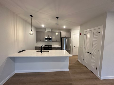 A kitchen with a white countertop and wooden flooring.