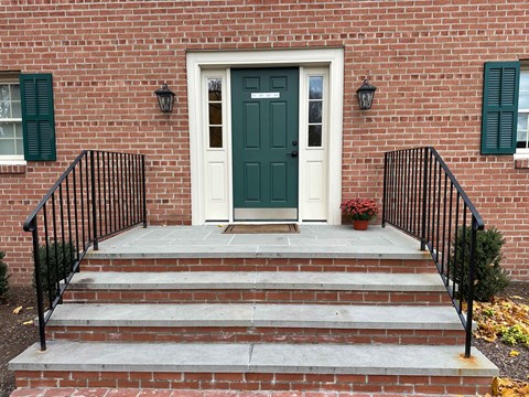 A brick house with a green door and steps leading up to it.