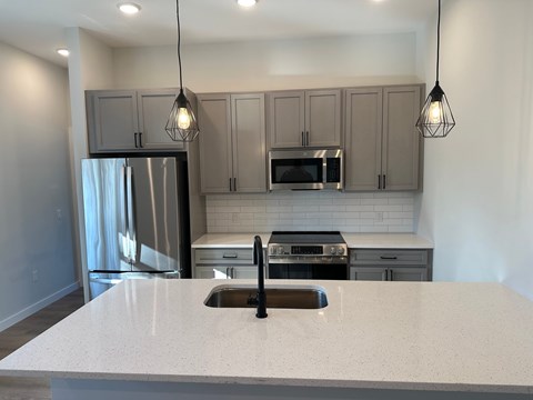 A kitchen with a white countertop and grey cabinets.