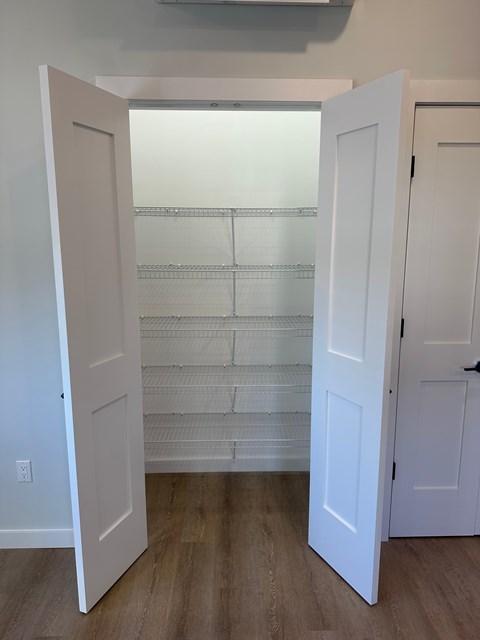 A white door is open to a room with a shelf.