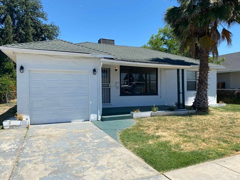 a white house with a white garage door and a palm tree