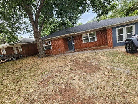 a small brick house with a tree in front of it