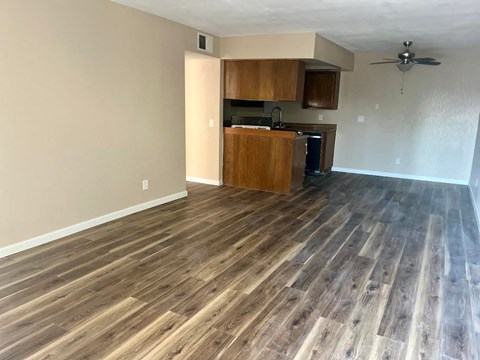 an empty living room with wood floors and a kitchen