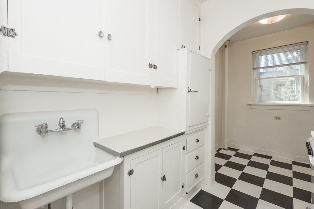 A white sink in a white bathroom with black and white checkered floor.