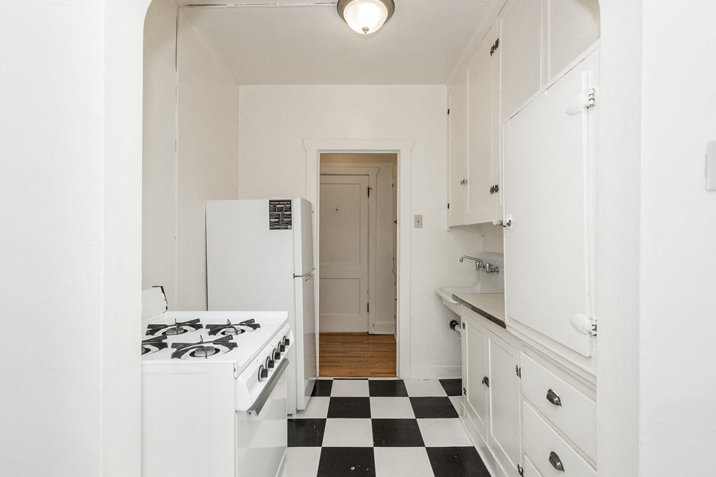 A white kitchen with a black and white checkered floor.